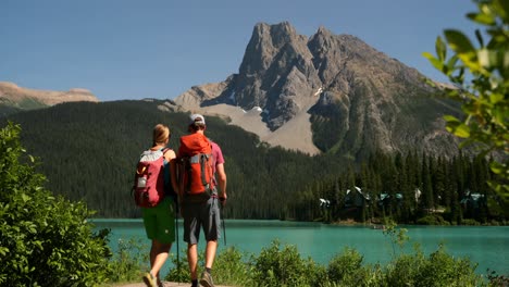 rear view of young caucasian hiker couple with backpack walking near riverside in the forest 4k