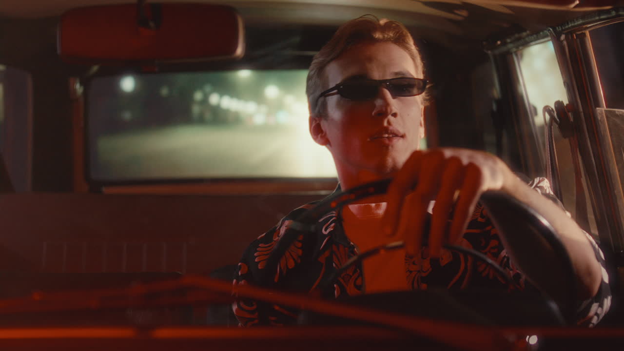 Young Man in Retro Car Enjoying Night Drive through City