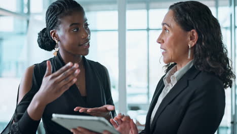 businesswomen discussing project on tablet in modern office