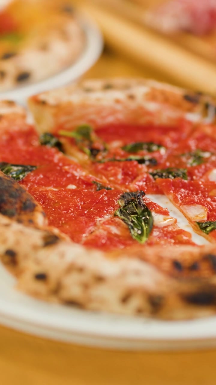 Mani prendono fette di pizza gourmet da piatti bianchi durante una cena sociale al ristorante