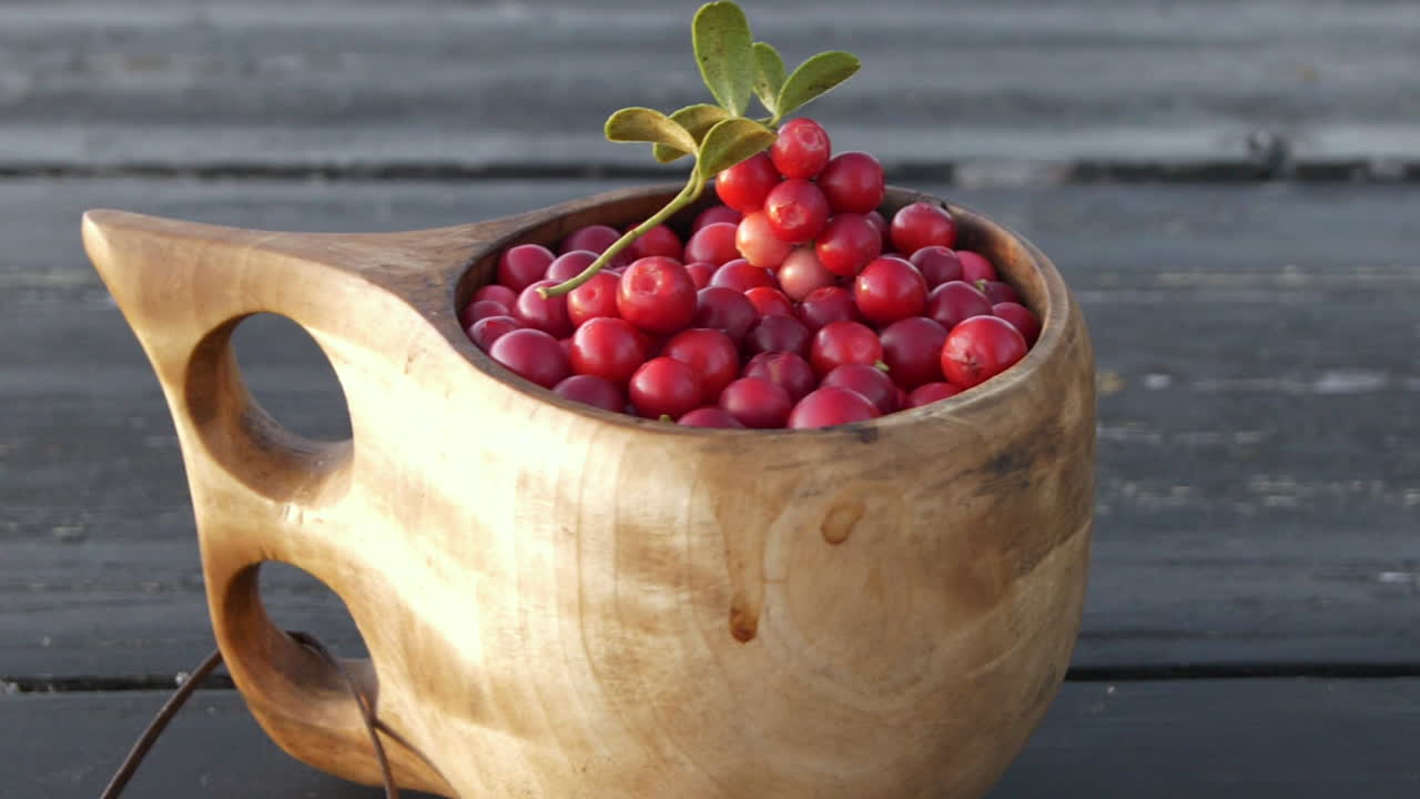 Close up of healthy Cranberries in a wooden cup, smooth pan