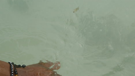 Hand-of-young-black-man-touching-clear-ocean-water