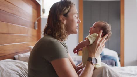 video of happy caucasian mother playing with newborn baby