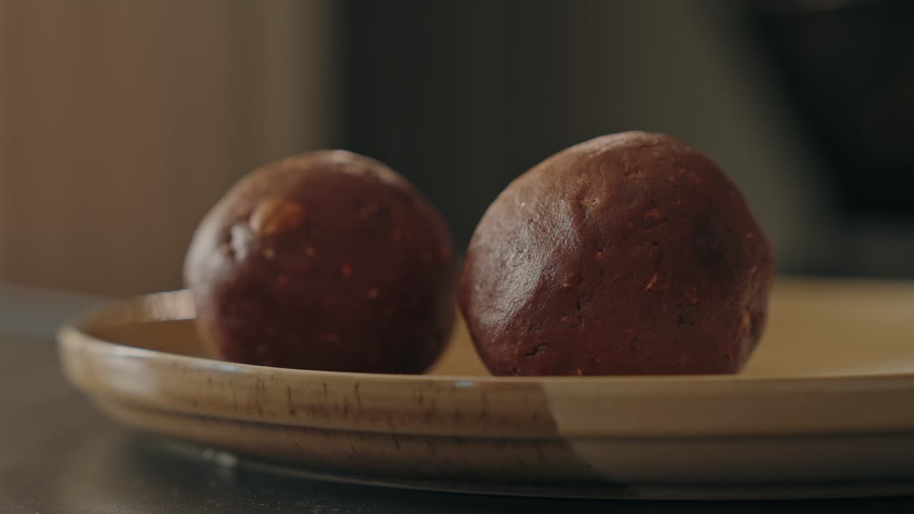 Primo piano di una mano che solleva un tartufo al cioccolato da un piatto su un tavolo interno
