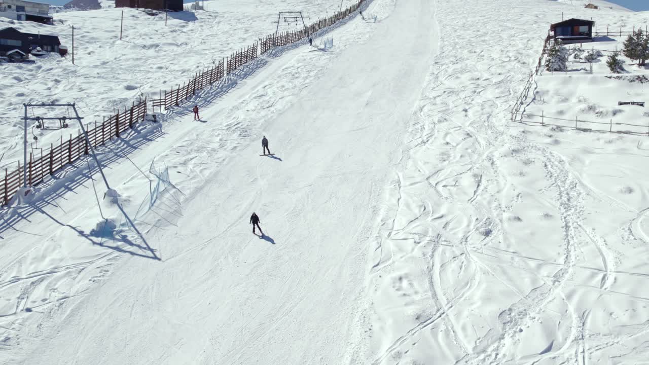 Slow motion shot of people skiing down a ski slope alongside a ski lift in the Farellones