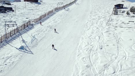 Slow-motion-shot-of-people-skiing-down-a-ski-slope-alongside-a-ski-lift-in-the-Farellones
