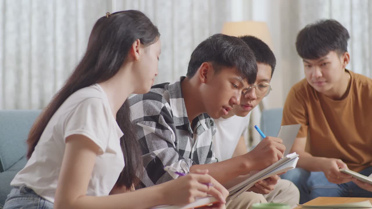 집에서 공부하는 아시아 십대 그룹의 클로즈업: 노트북과 책을 가진 학생들이 노트북에 글을 쓰고, 프로젝트에서 성공을 축하하며, 하이파이브 제스처를 합니다.