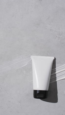 vertical video of beauty product tube in water with copy space on white background