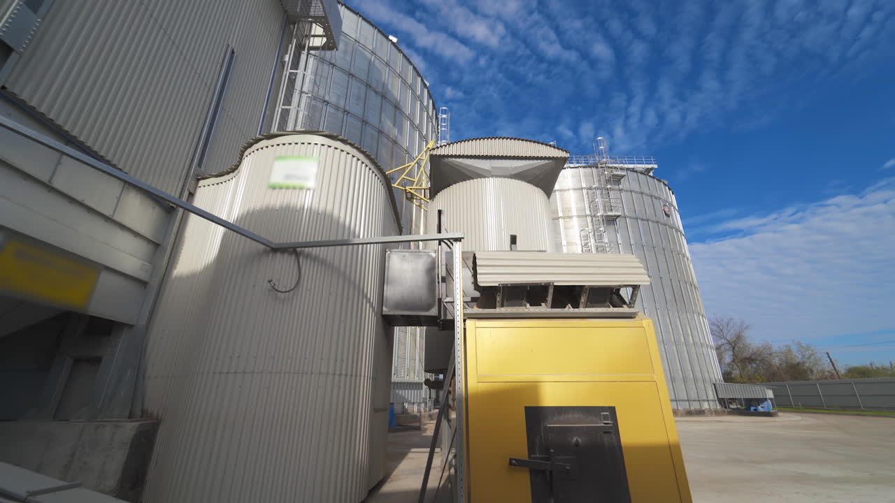 Modern Granary elevator. Silver silos on agro-processing and manufacturing plant for processing drying cleaning and storage of agricultural products, flour, cereals and grain.
