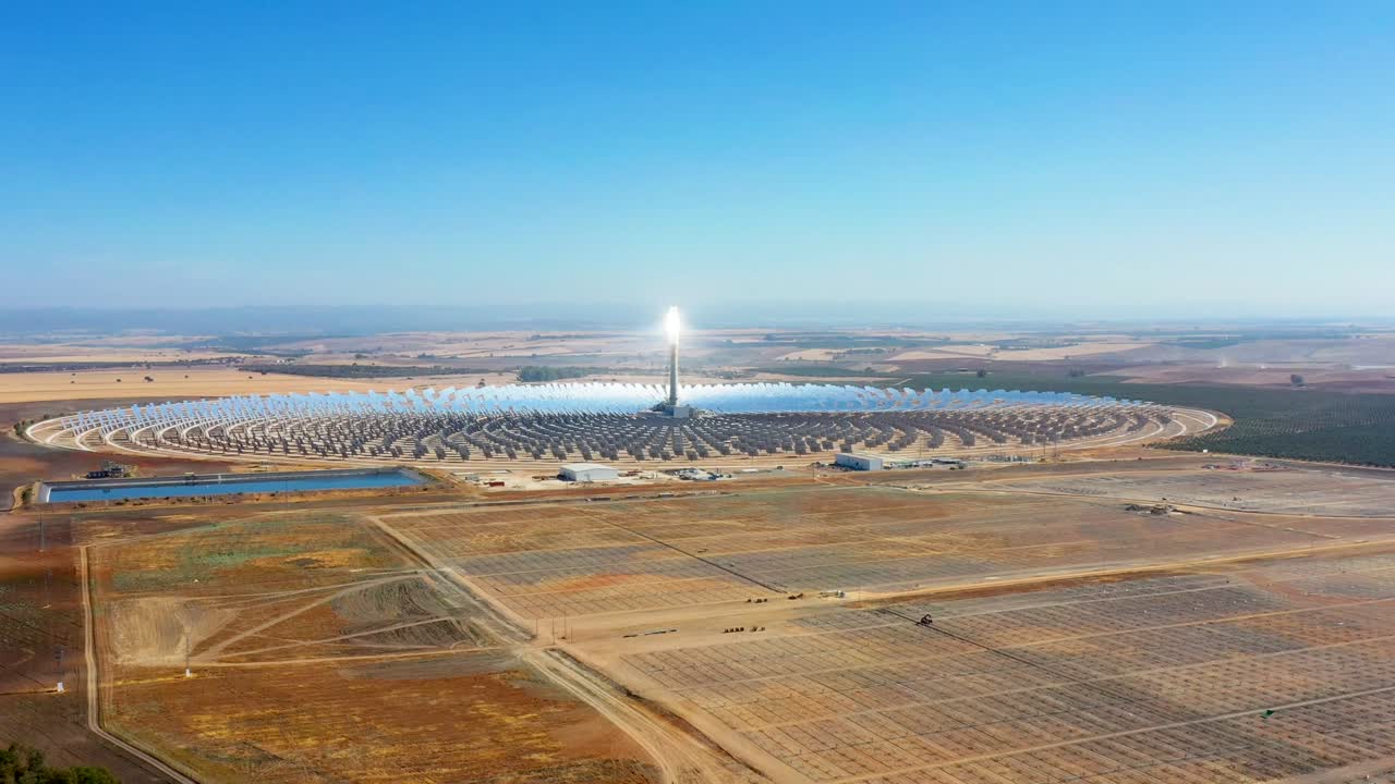 una gran planta solar térmica utiliza espejos que enfocan los rayos solares en una torre de recolección para producir energía renovable y libre de contaminación - vista aérea con un avión no tripulado