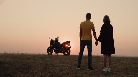 The-romantic-couple-holds-hands-by-a-motorcycle