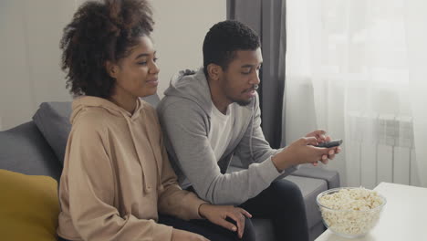 pareja joven escogiendo una película con el control remoto