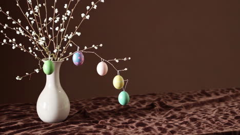 colorful easter eggs hanging from branches in a vase