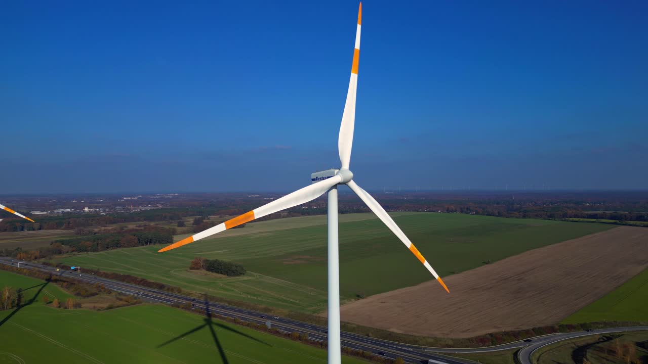 Wind turbine standing in green field next to highway autobahn in autumn Germany, generating renewable energy. Unique aerial view flight panorama overview drone