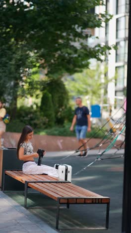 young woman with suitcase in city park