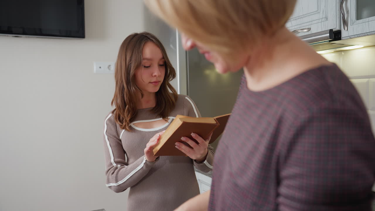아이가 요리 책을 읽고 그녀의 행동을 감독하는 동안 부에서 는 여자의 클로즈업, 어린 소녀는 지침을 주의 깊게 따르고 있습니다.
