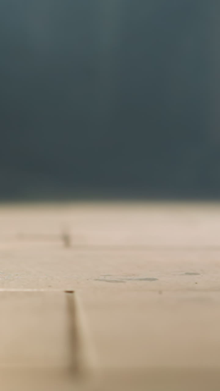 타일로 된 바닥에 떨어지는 스마트폰의 클로즈업 뷰, 바닥에 부힌 후 공중에 회전하는 모습