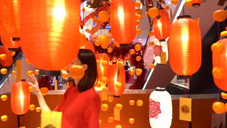 Beautiful-Asian-woman-walking-through-a-department-store-looking-at-orange-Chinese-lamps-or-lanterns---slow-motion