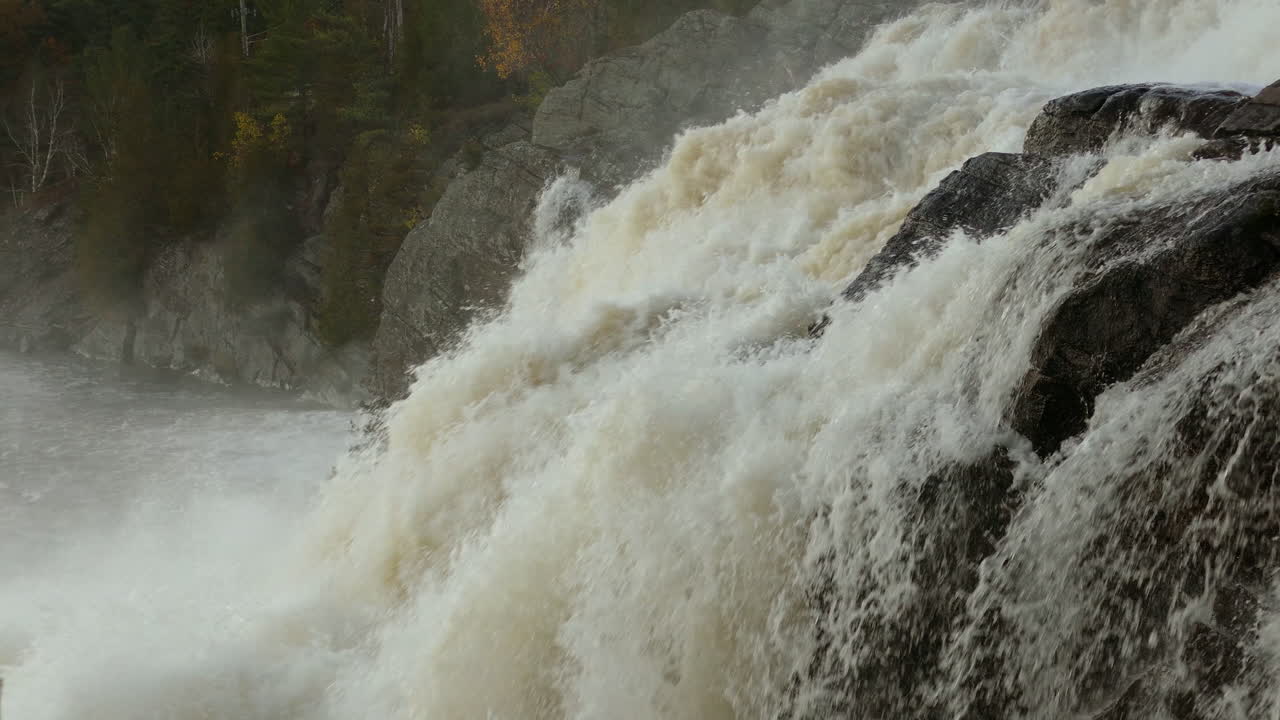 Powerful waterfall flowing down the rocks, water splashing, Close-up shot,