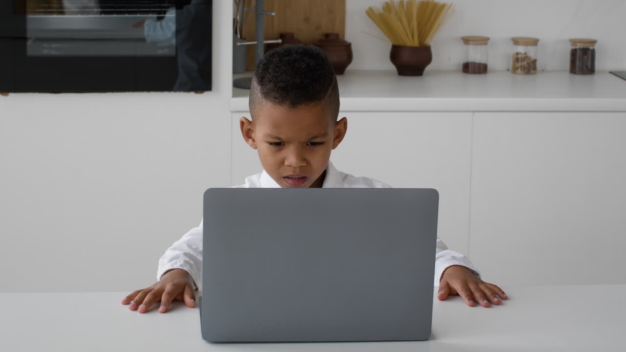 Child using laptop in kitchen