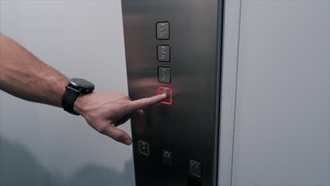 close-up shot male hand press metal button to call the elevator after which it glows red floor slow motion