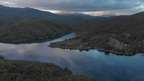 Drone-mountain-lake-reflecting-colorful-sunset-clouds-tilt-up-mountain-peaks