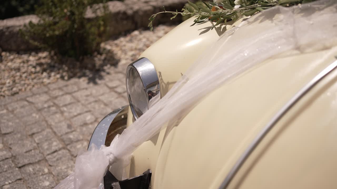 Close up of a vintage Volkswagen Beetle adorned with white wedding ribbons