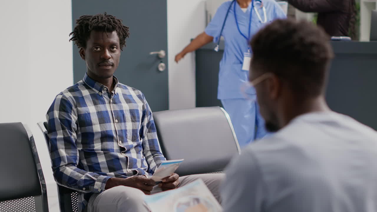 Young male person reading medical fliers in clinic lobby