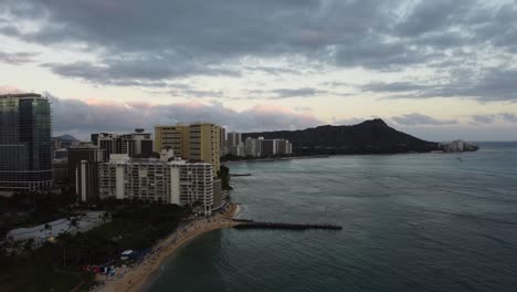 4k cinematic crane drone shot of waikiki beach and diamond head illuminated by the orange tint from the sunset in oahu