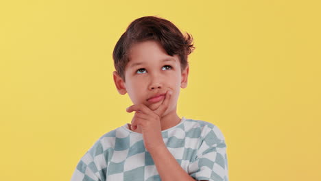 boy thinking and looking up on yellow background