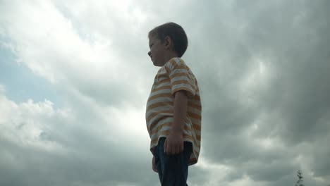 a young boy looking up at the sky in slow motion, his eyes full of wonder and curiosity. this cinematic footage captures the innocence and imagination of childhood.