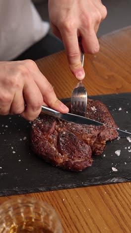 person cutting steak with fork and knife