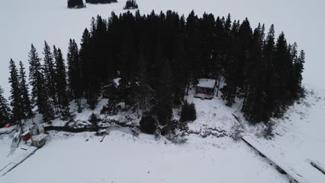 A-Rising-Drone-Shot-of-a-remote-isolated-cabin-Island-on-Frozen-Canadian-Paint-Lake