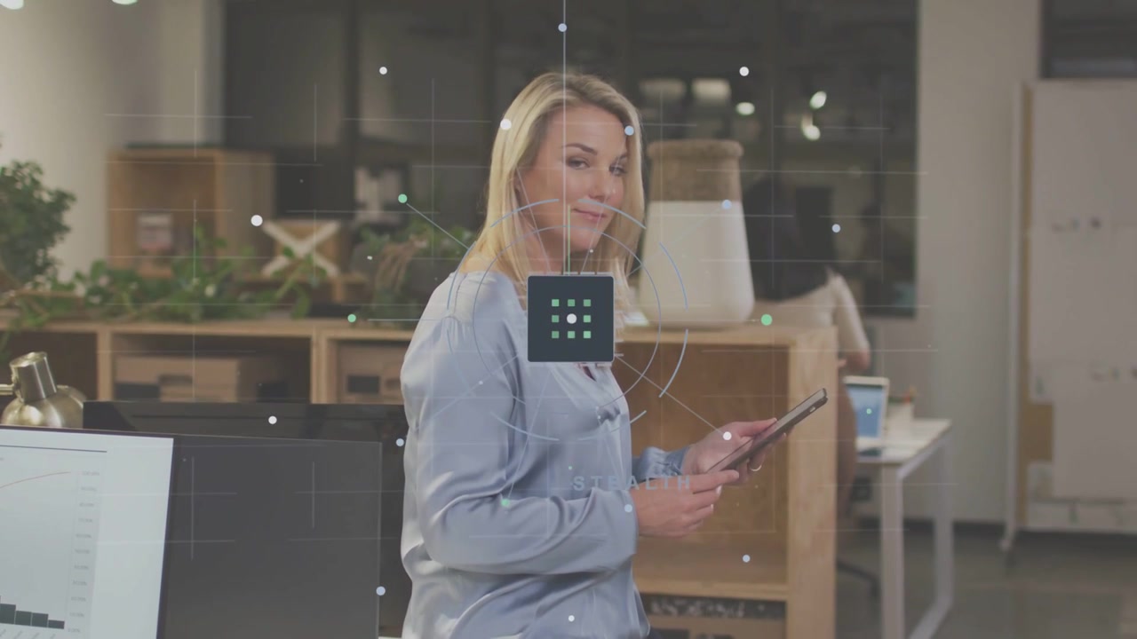 Seated woman tapping tablet, initiating UI grid over torso, checking data as tech peer passing by