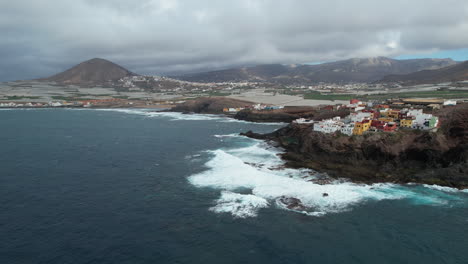 aerial view of powerful ocean waves breaking against rocky coastal landscape of galdar, revealing dramatic gran canaria shoreline with expansive atlantic waters and rugged terrain