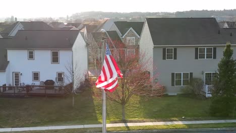 american flag waving in golden light with houses in background