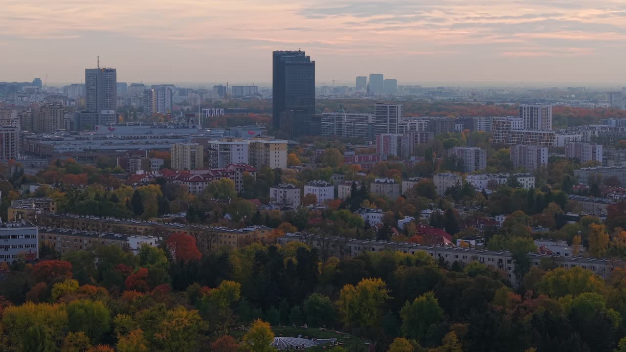Vista aérea de Varsóvia, Polónia, ao crepúsculo outonal enevoado, sobrevoando um bairro residencial com edifícios comerciais ao fundo.