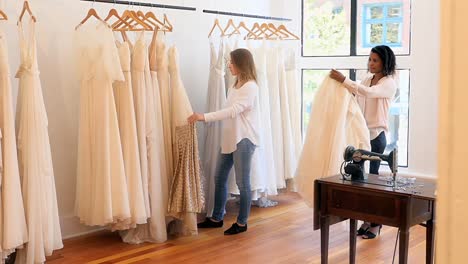 female fashion designers arranging dress on clothes rail