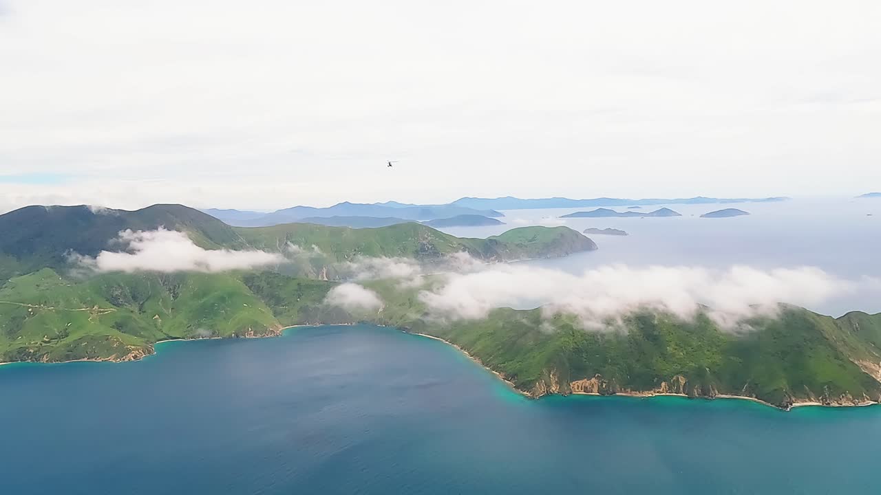 Helicopter flying high over the white cloud covered, Marlborough sounds towards the west, New Zealand