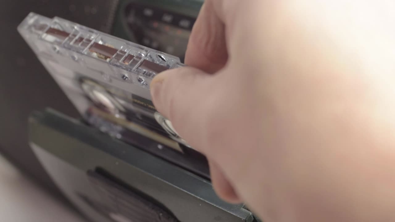 Primo piano di una mano che inserisce cassette retrò in un lettore di cassette radio