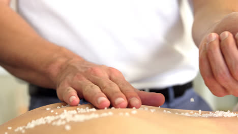 Woman-receiving-salt-scrub-therapy-from-physiotherapist