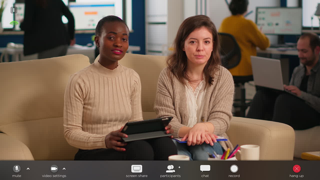 Team from start up company talking during video meeting sitting on couch