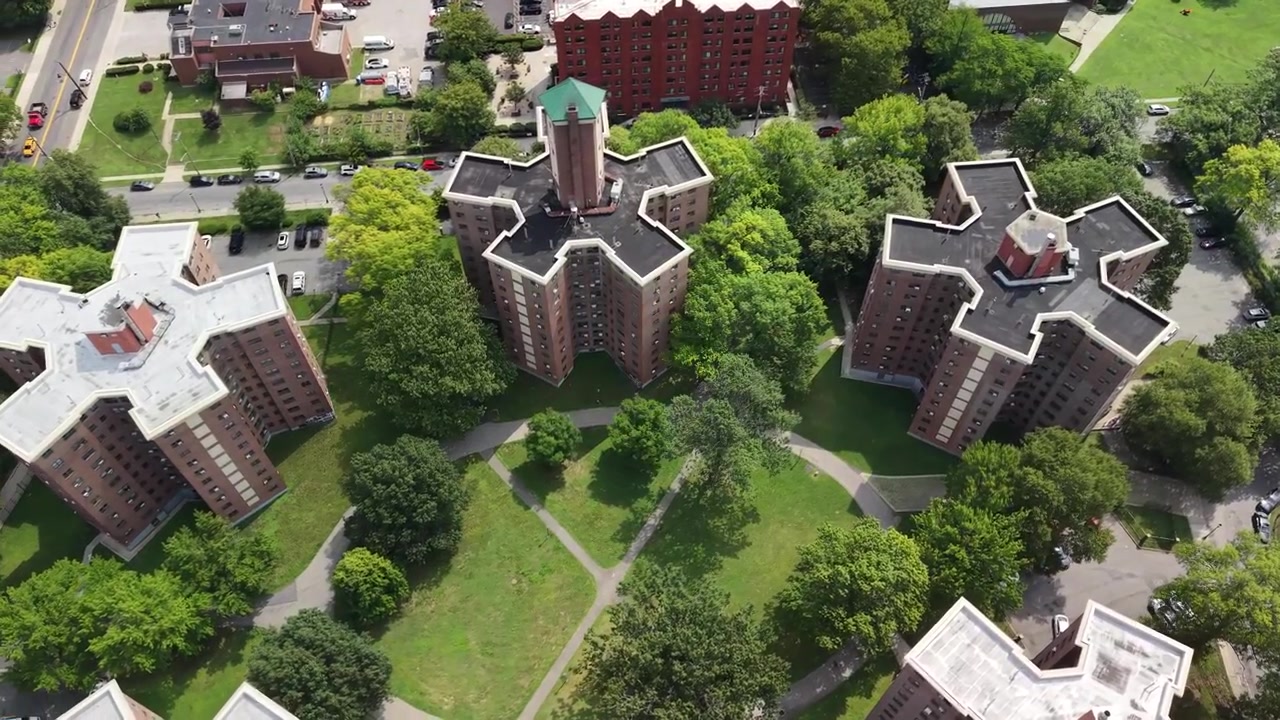 Uniek luchtperspectief dat de symmetrische architectuur toont van stervormige sociale huurappartementencomplexen omringd door weelderige groene bomen in een residentiële voorstedelijke gemeenschap