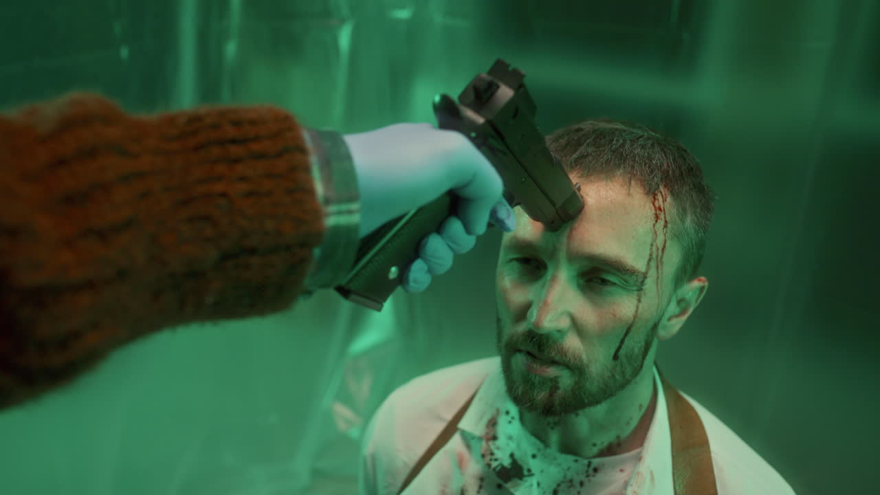 hombre torturado hablando con el asesino con un arma presionada contra su frente