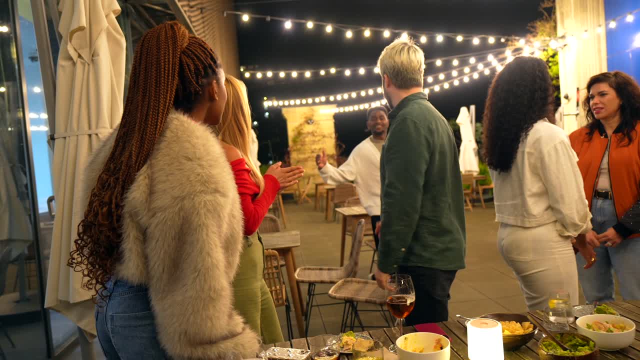Group of people gathering around a table at an outdoor party