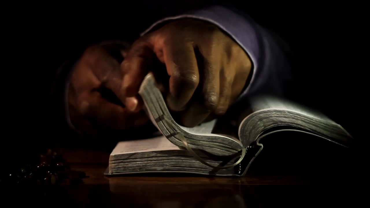 hombre rezando a dios con las manos junto con la biblia hombre caribeño rezando con fondo negro almacen de video