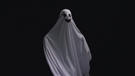 niño vestido con disfraces de fantasma trucos o tratamientos en halloween asustando a la gente corriendo contra un fondo negro 2