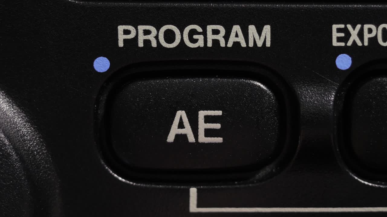 Macro close up of program AE button being pressed on camera control panel