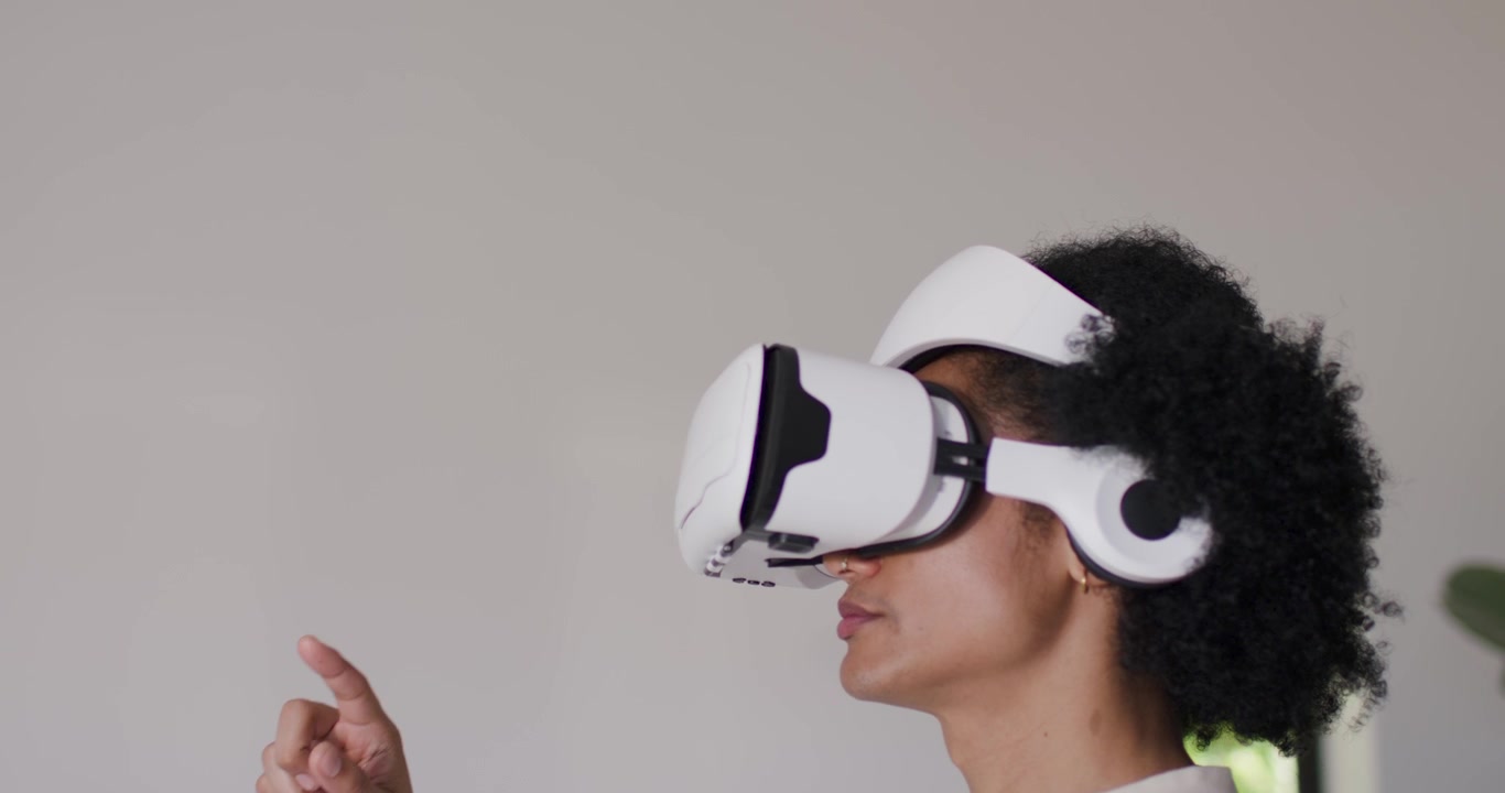 Uomo che indossa un visore VR bianco vicino alla finestra, che segue un'indicazione, alzando l'indice destro, con spazio per il testo.