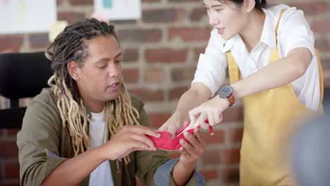 busy diverse designers discussing shoe in fashion design studio, in slow motion